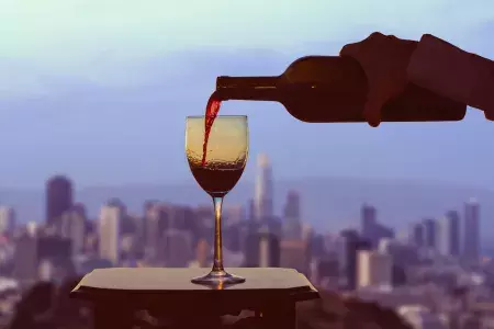 A glass of red wine being poured, with the San Francisco skyline visible out the window.