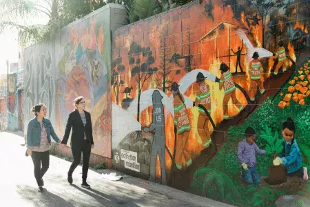 A female couple walk past a San Francisco mural.