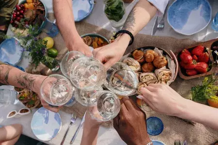 Foto aérea de um grupo de pessoas tilintando copos em uma mesa de brunch.
