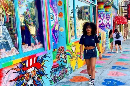 Woman walking down Haight Street with a colorful mural in the background.