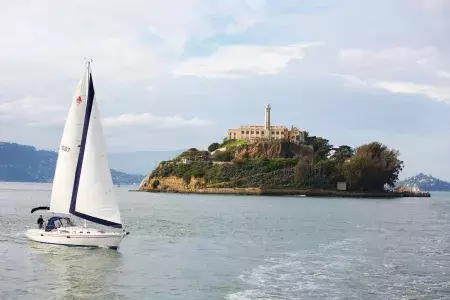 A sailboat passes in front of Alcatraz Island in San Francisco.