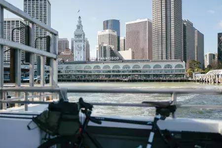 Bicicleta encostada em um trilho com o Ferry Building ao fundo.