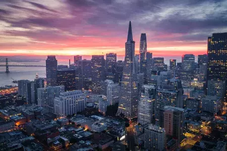 Aerial view of the San Francisco skyline at twilight, with the Transamerica Building and Bay Bridge visible.