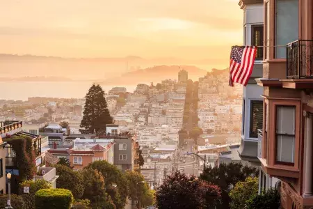 丘の頂上から見たサンフランシスコの眺め。前景にはアメリカ国旗がはためいています。