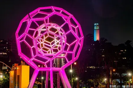 Buckyball shines outside the Exploratorium, with Coit Tower in the background