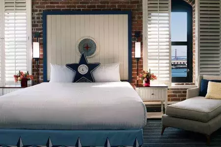 Image of room at argonaut hotel, bed and view of Golden Gate Bridge in window.