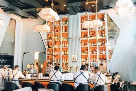 Interior of the Proper Hotel bar, large orange and blue bar with white, floral-eque light fixtures