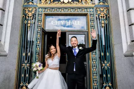 Couple posing in front of city hall after wedding