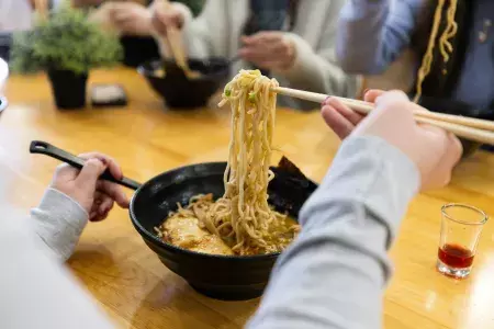 箸で丼からラーメンを持ち上げる人