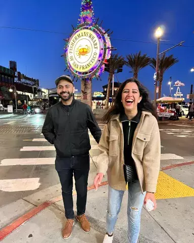 A happy couple visit San Francisco's Fisherman's Wharf at night.