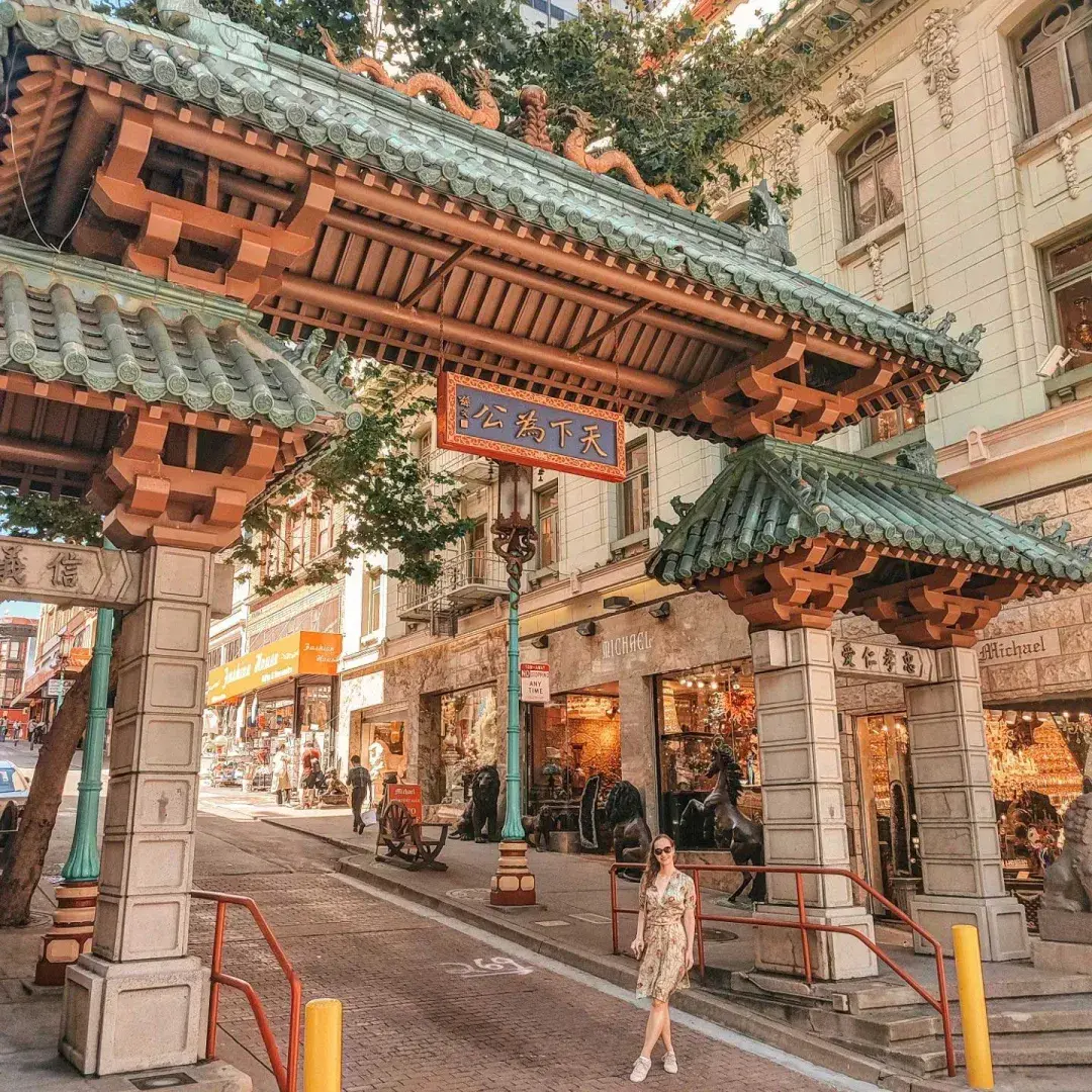 한 여성이 샌프란시스코 Chinatown 입구를 표시하는 화려한 문 앞에서 포즈를 취하고 있다.