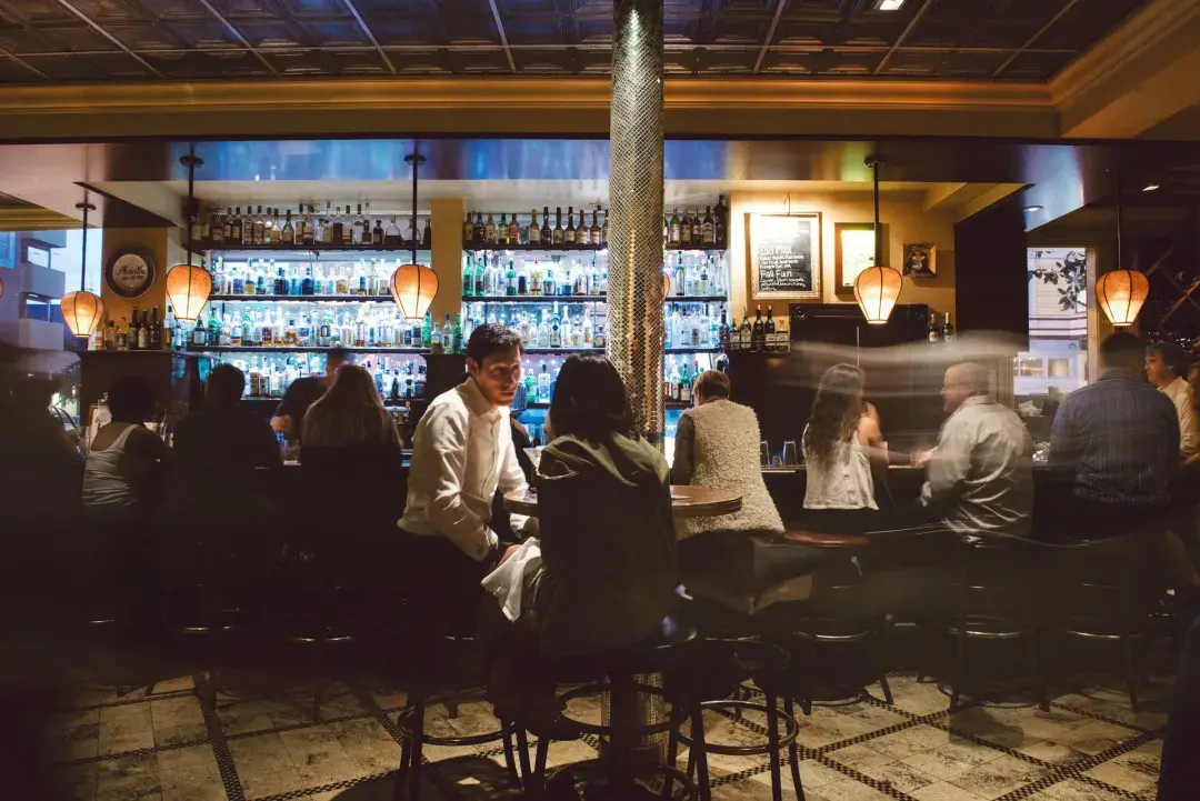 A couple share drinks at a busy San Francisco bar.