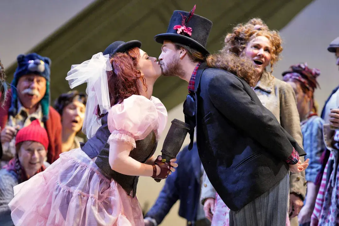 Two actors in costume kiss during a performance of Don Giovanni.
