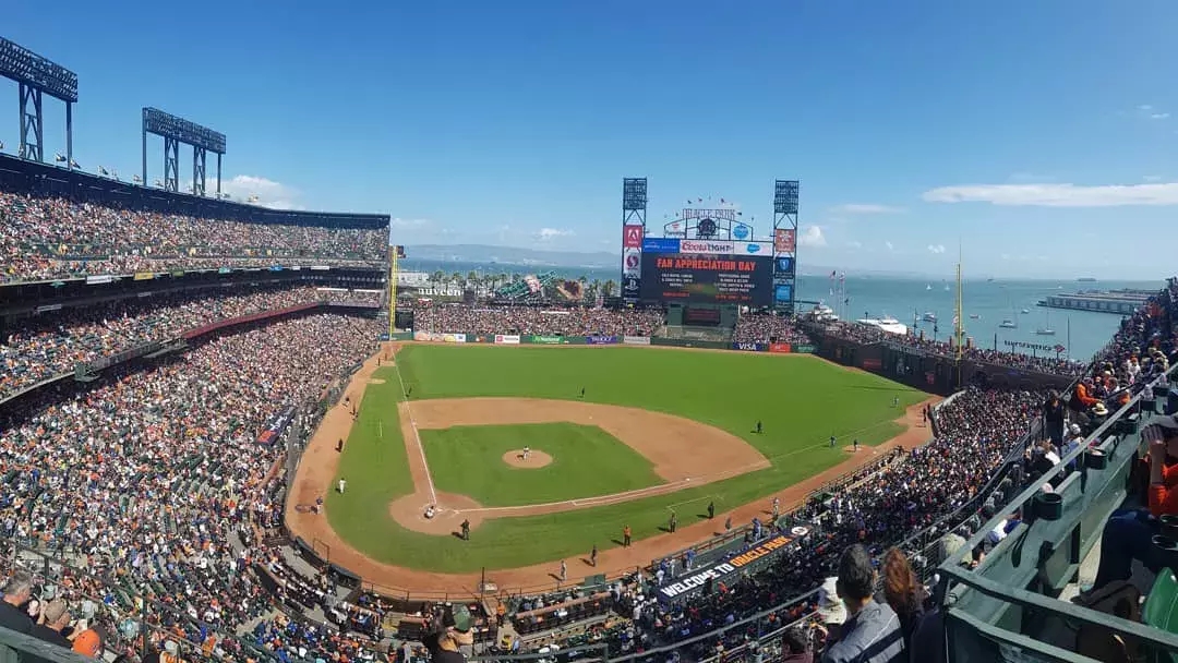 A view of San Francisco's Oracle Park looking out from the stands, with the baseball diamond in the foreground and San Francisco Bay in the background.