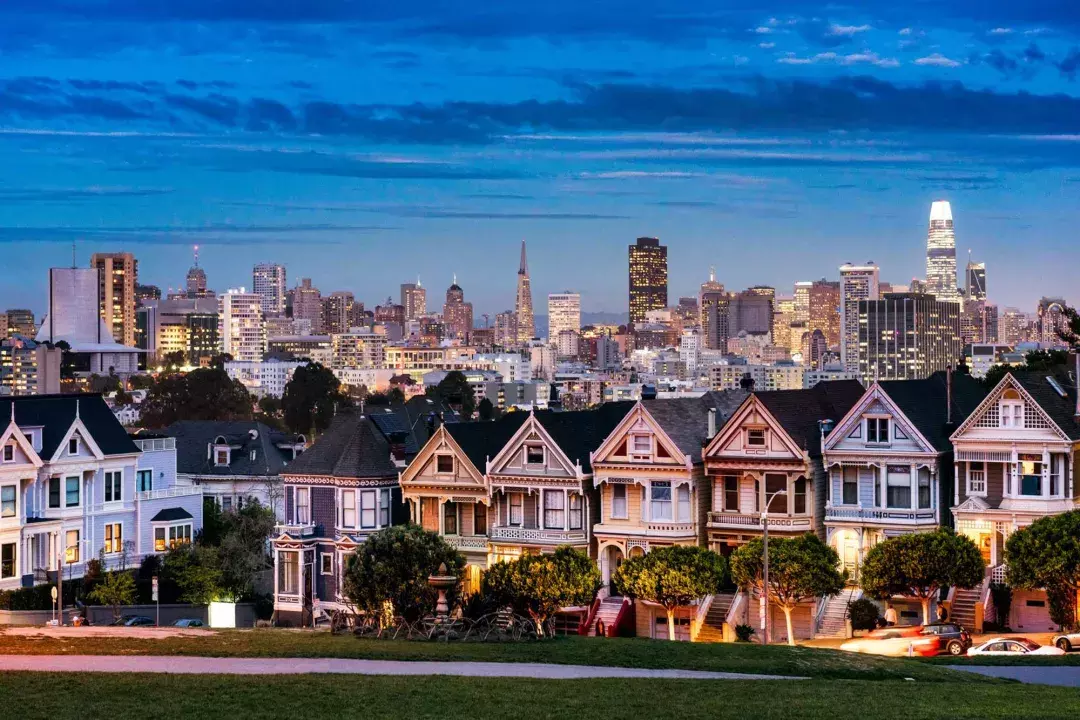 The famous Painted Ladies of Alamo Square are pictured before the San Francisco skyline at twilight.