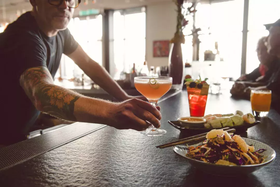 A bartender serves a patron a cocktail at a bar in San Francisco.