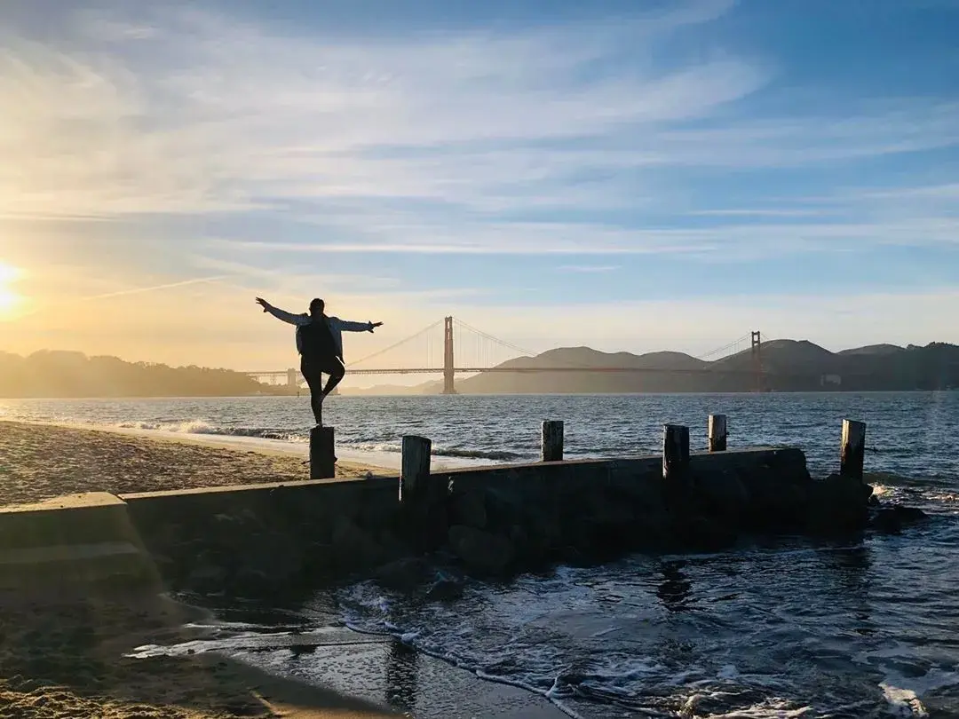 Uma mulher está em um píer no bairro Marina de São Francisco, olhando para a Golden Gate Bridge .