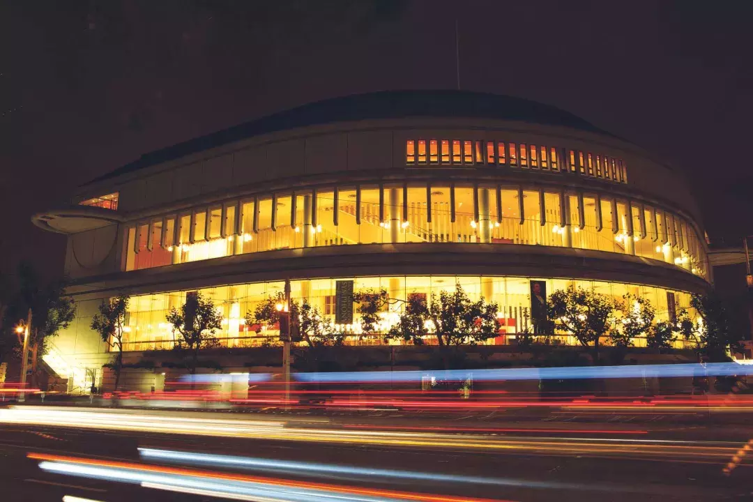 Exterior of the Louise M. Davies Symphony Hall at night with streaks of light from passing vehicles.