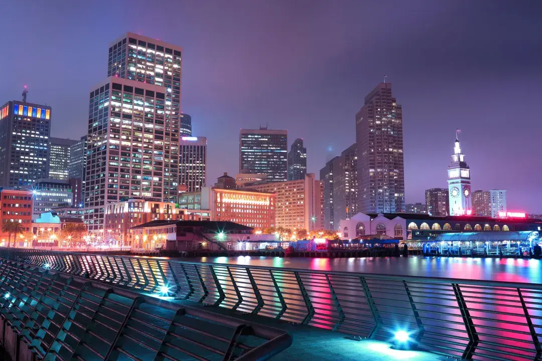 San Francisco's Embarcadero is lit up at night in an array of pastel colors.