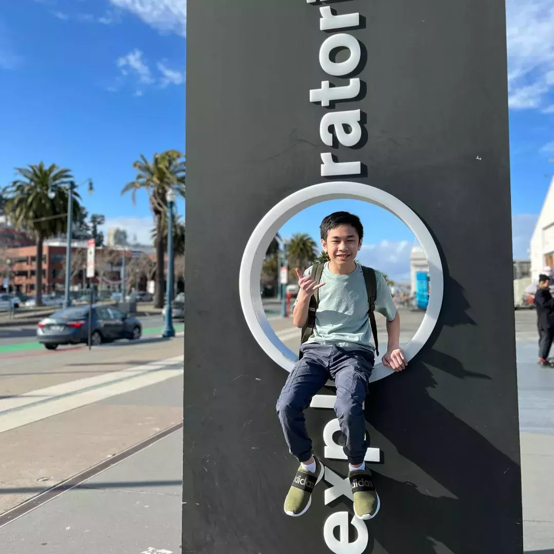 Child sitting on Exploratorium sign 