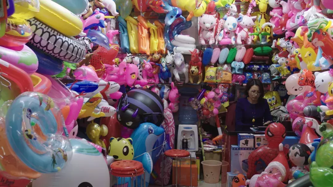 Image of woman surrounded by blow up animals in small room. 