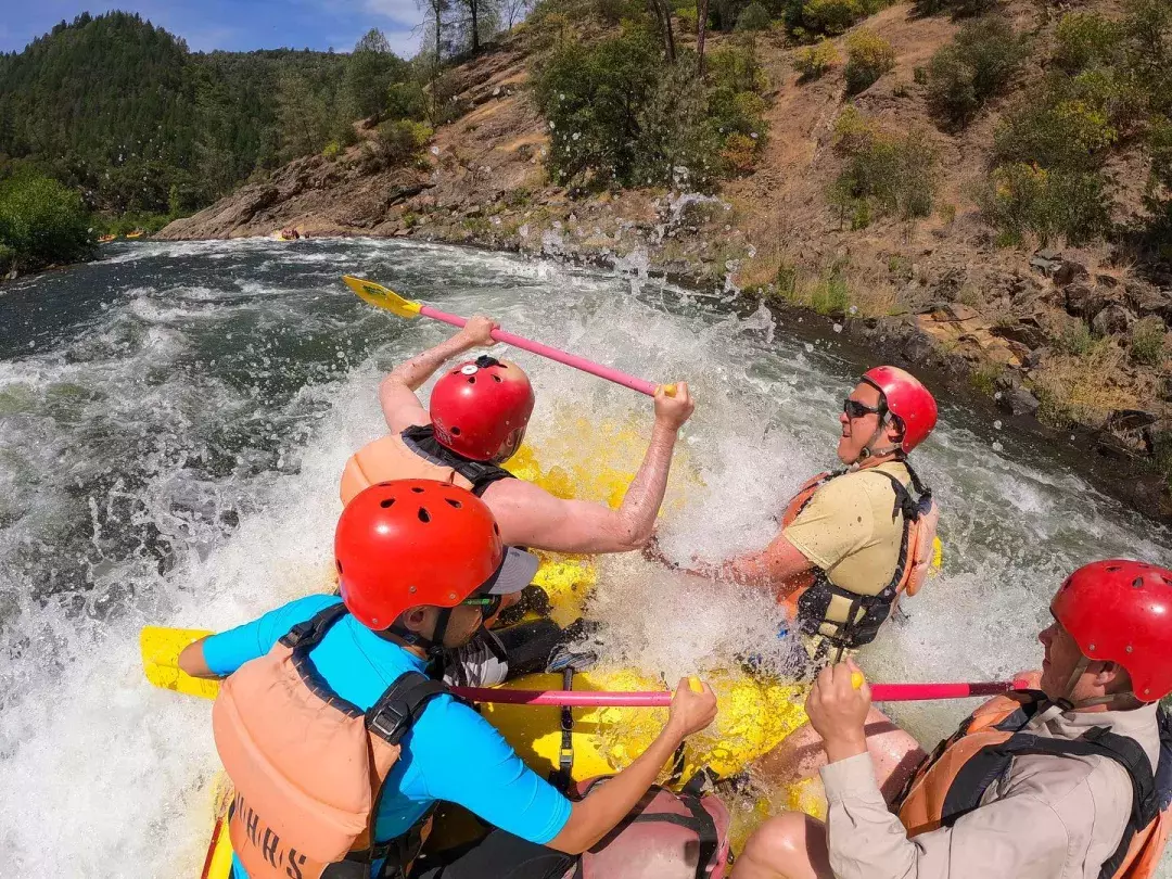 Group of people getting splashed while river rafting on the American River