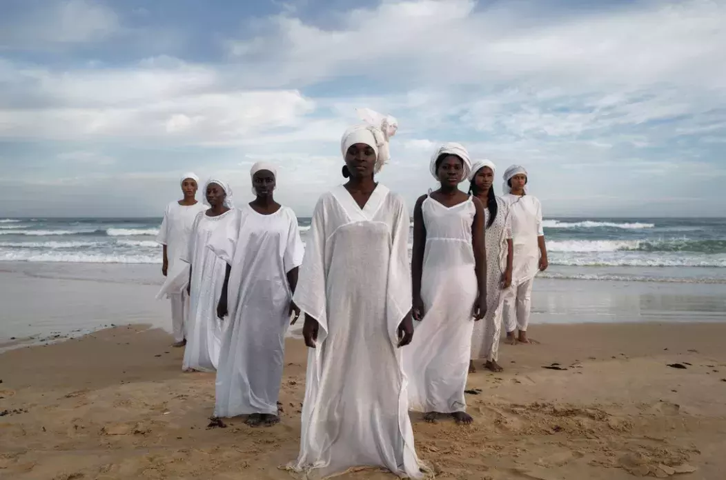 Women in white flowing outfits standing in front of an ocean