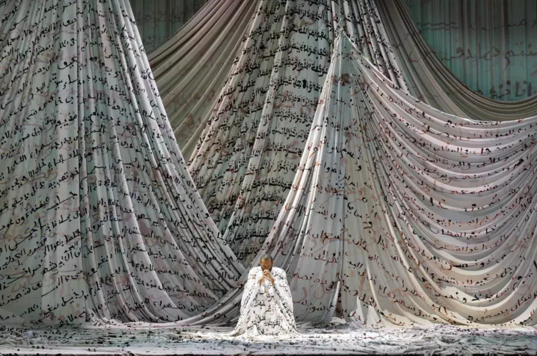 Man kneeling in front of large swathes of printed fabric 