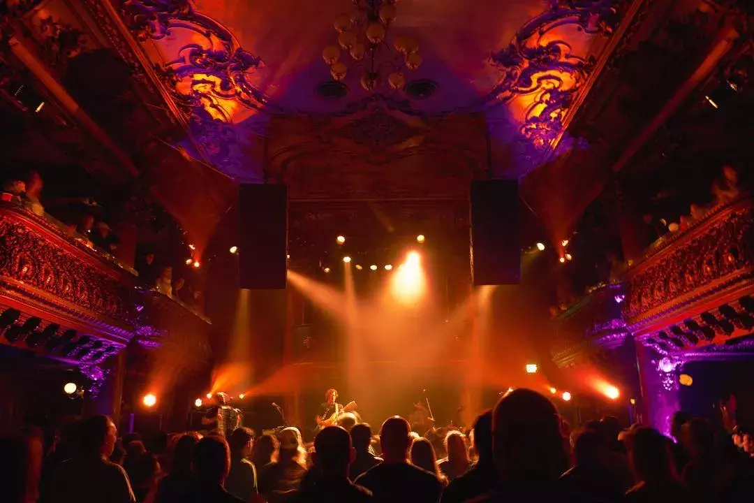 Image of concert hall with pink and purple colored lights 