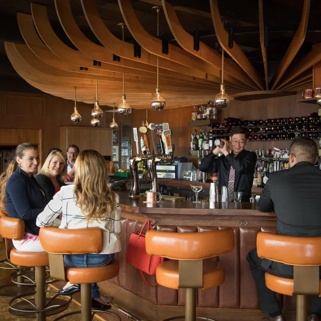 Man shaking cocktail at Stoma's bar with people seated around him 