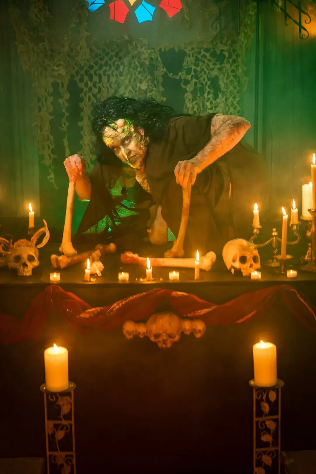 A witch hunched over a table with bones 