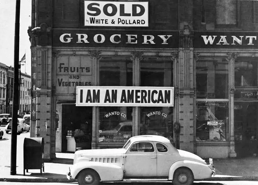 Vintage image of a sign reading "I Am an American" on a grocery store.