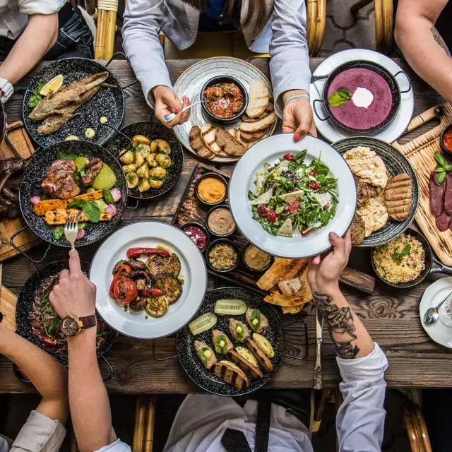 Pessoas sentadas à mesa de jantar, compartilhando comida.