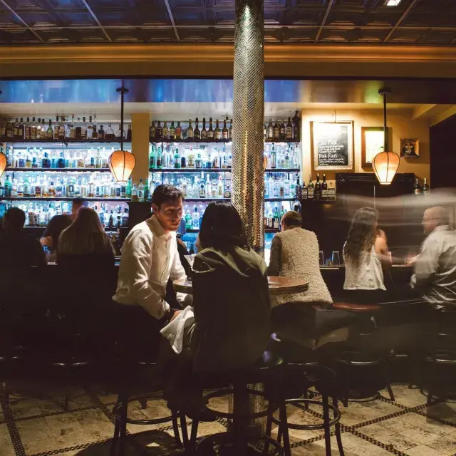 A couple share drinks at a busy San Francisco bar.