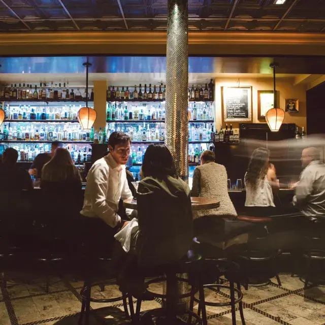 A couple share drinks at a busy San Francisco bar.