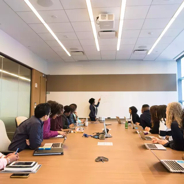 Woman up at the whiteboard leading a meeting.
