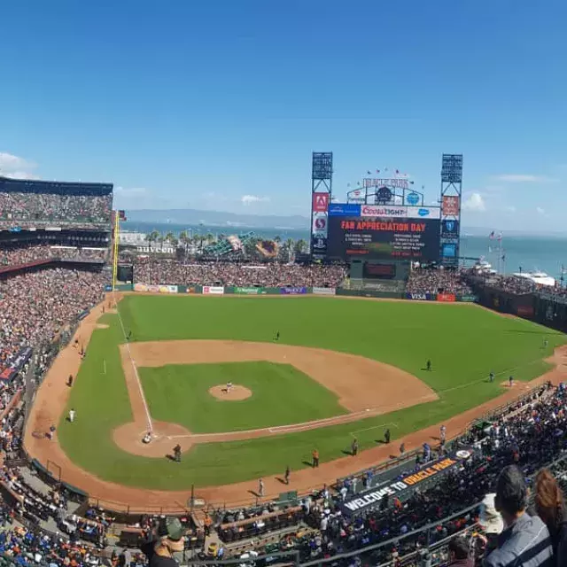 A view of San Francisco's Oracle Park looking out from the stands, with the baseball diamond in the foreground and San Francisco Bay in the background.