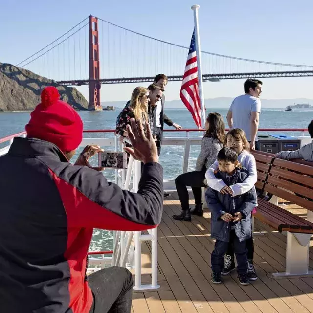 A family enjoys a cruise on the bay, passing the Golden Gate Bridge.