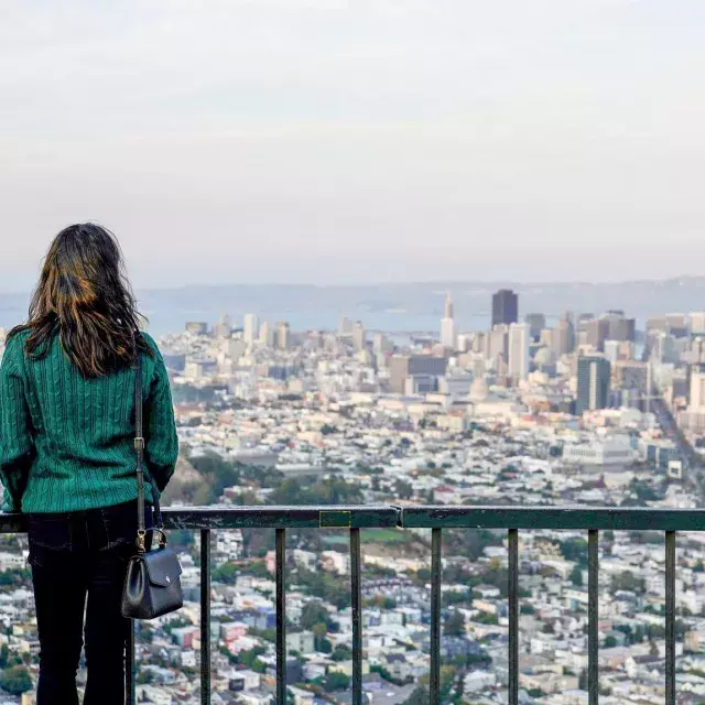 A woman looks at the San Francisco skyline from Twin Peaks.