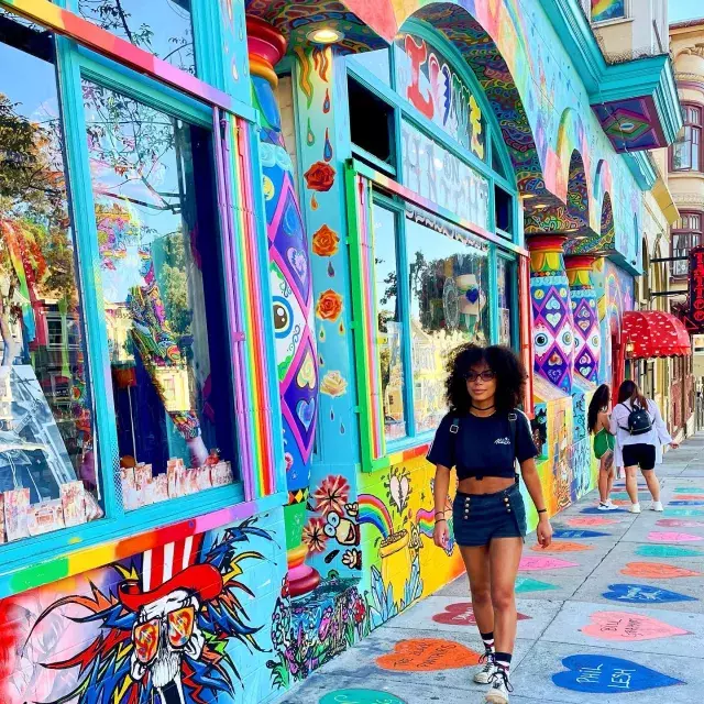 Woman walking down Haight Street with a colorful mural in the background.