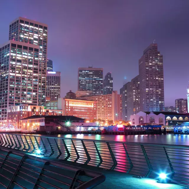 San Francisco's Embarcadero is lit up at night in an array of pastel colors.