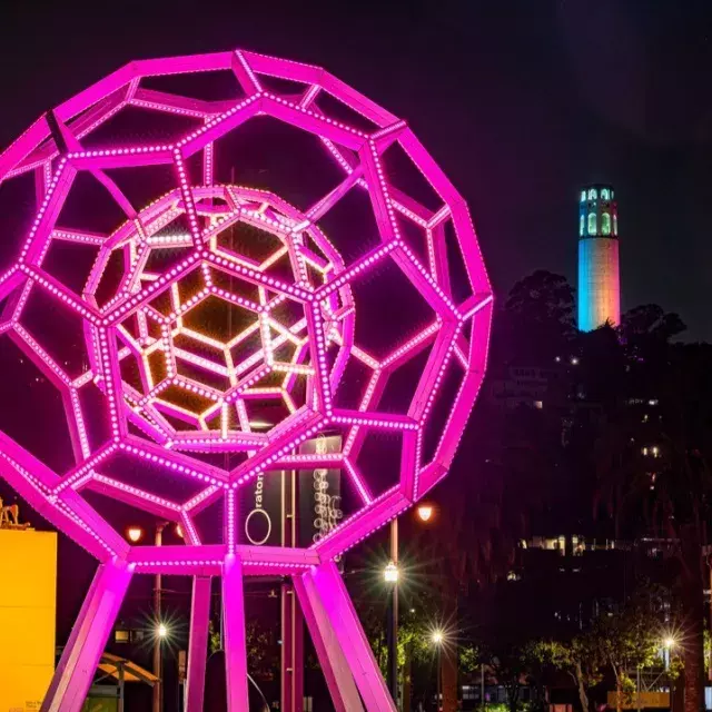 Buckyball shines outside the Exploratorium, with Coit Tower in the background