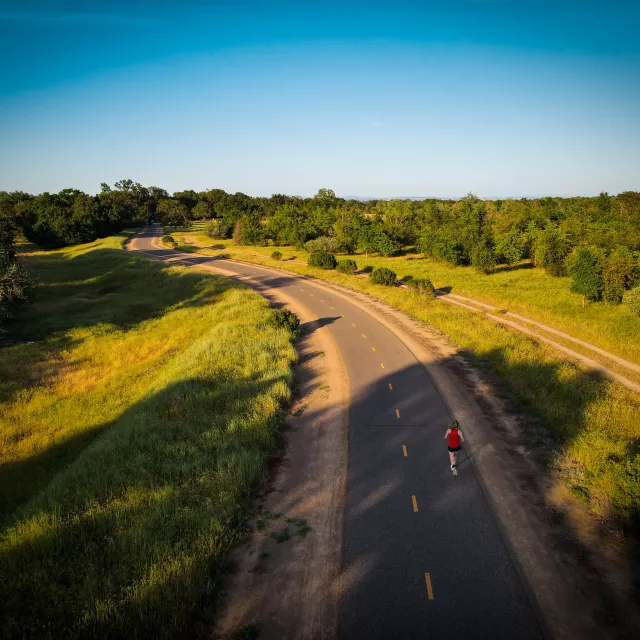 Overhead shot of woman running on a road through the countryside