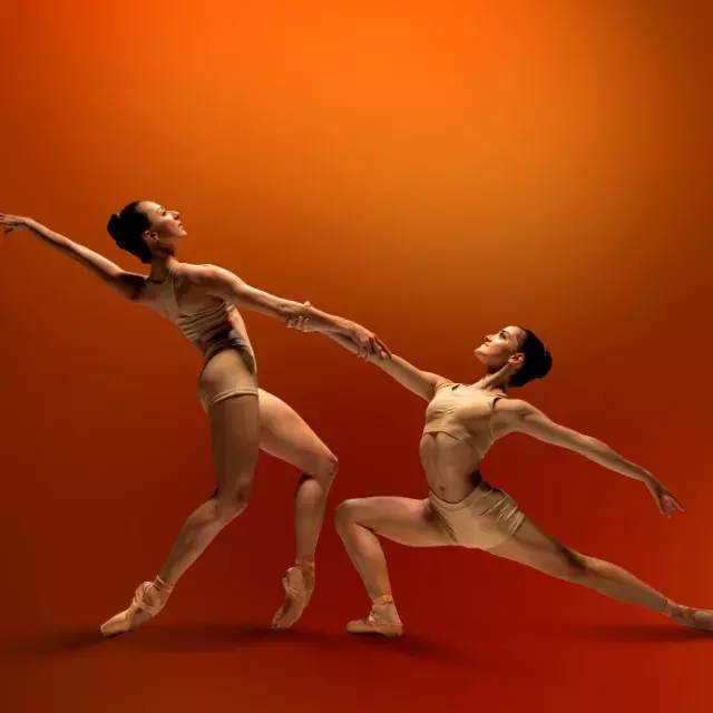 SF ballet dancers holding hands on a red background 