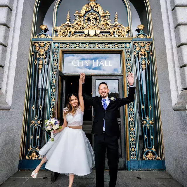 Couple posing in front of city hall after wedding