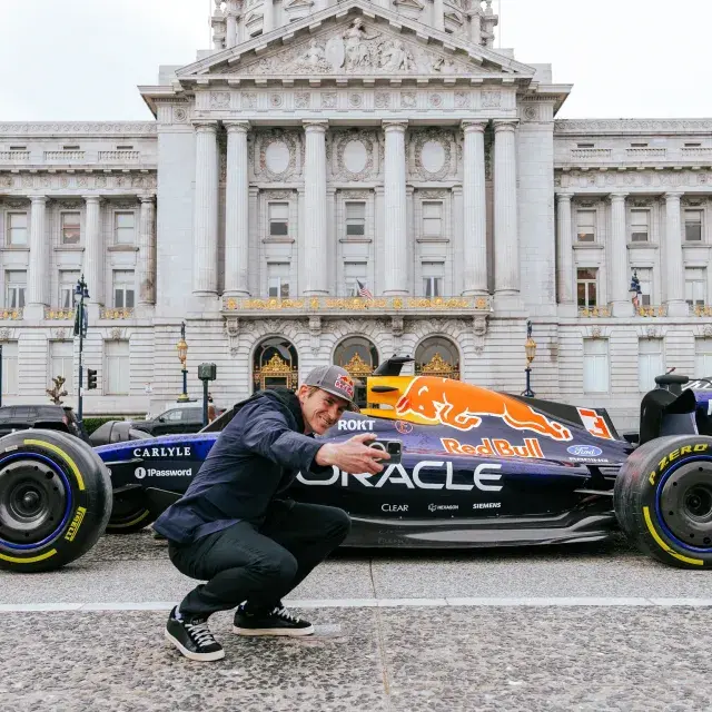 Scott Speed stands in front of a Red Bull Racing F1 car outside San Francisco City Hall.
