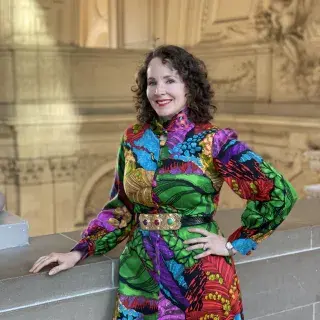Kate Patterson posing in a colorful dress inside City Hall. 