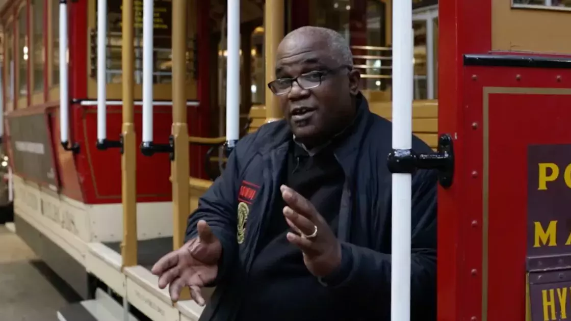 Ellis Cato sitting on a cable car.