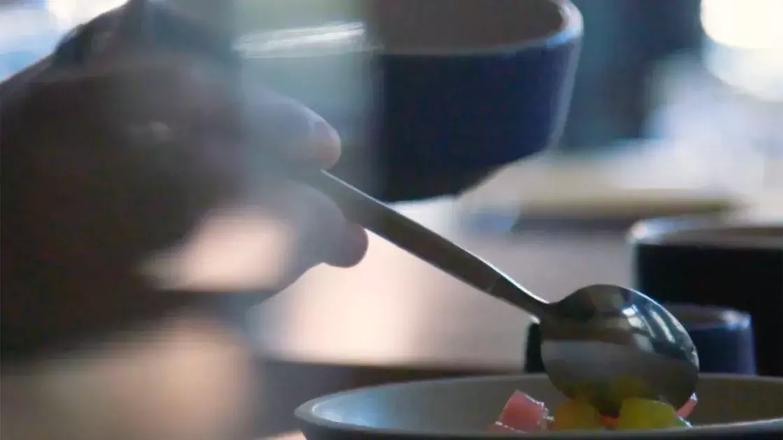 A ladle pours sauce over a plate of food.